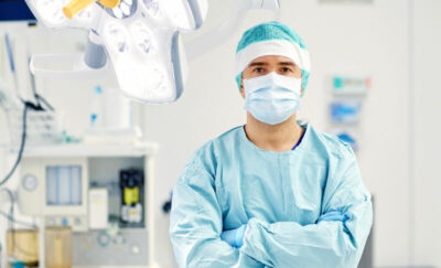 A young doctor in surgery clothes looking into the camera.