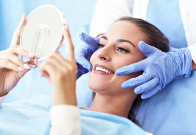 A woman looking into the small mirror on her new perfect white teeth.