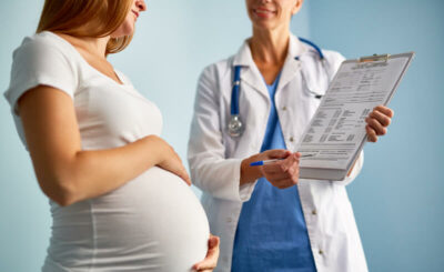 A pregnant woman with a doctor who is showing her something on the form.