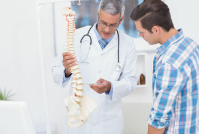 Doctor showing a man a model of a spine, explaining surgery.